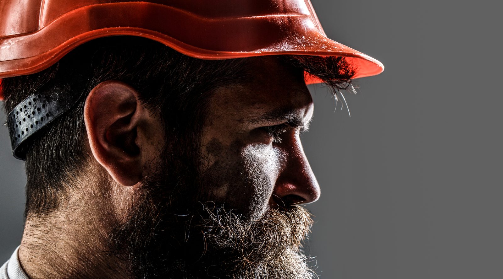 Close-up profile of a construction worker in a hard hat at the end of a shift