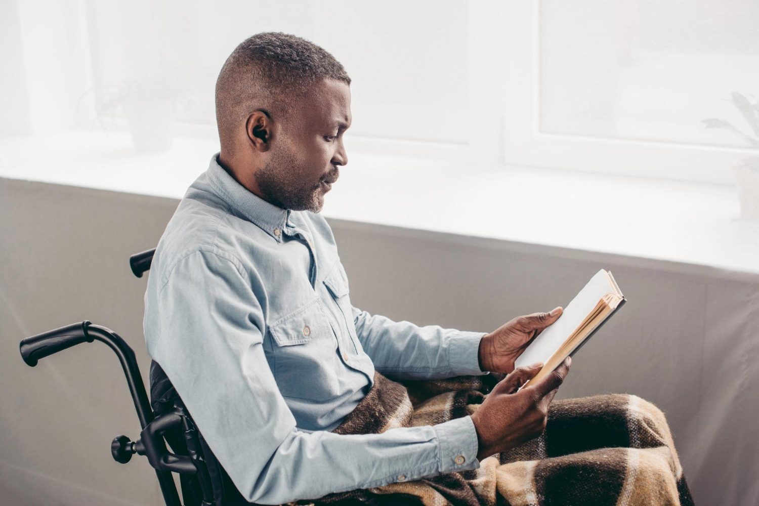 A man using a wheelchair reads quietly at home
